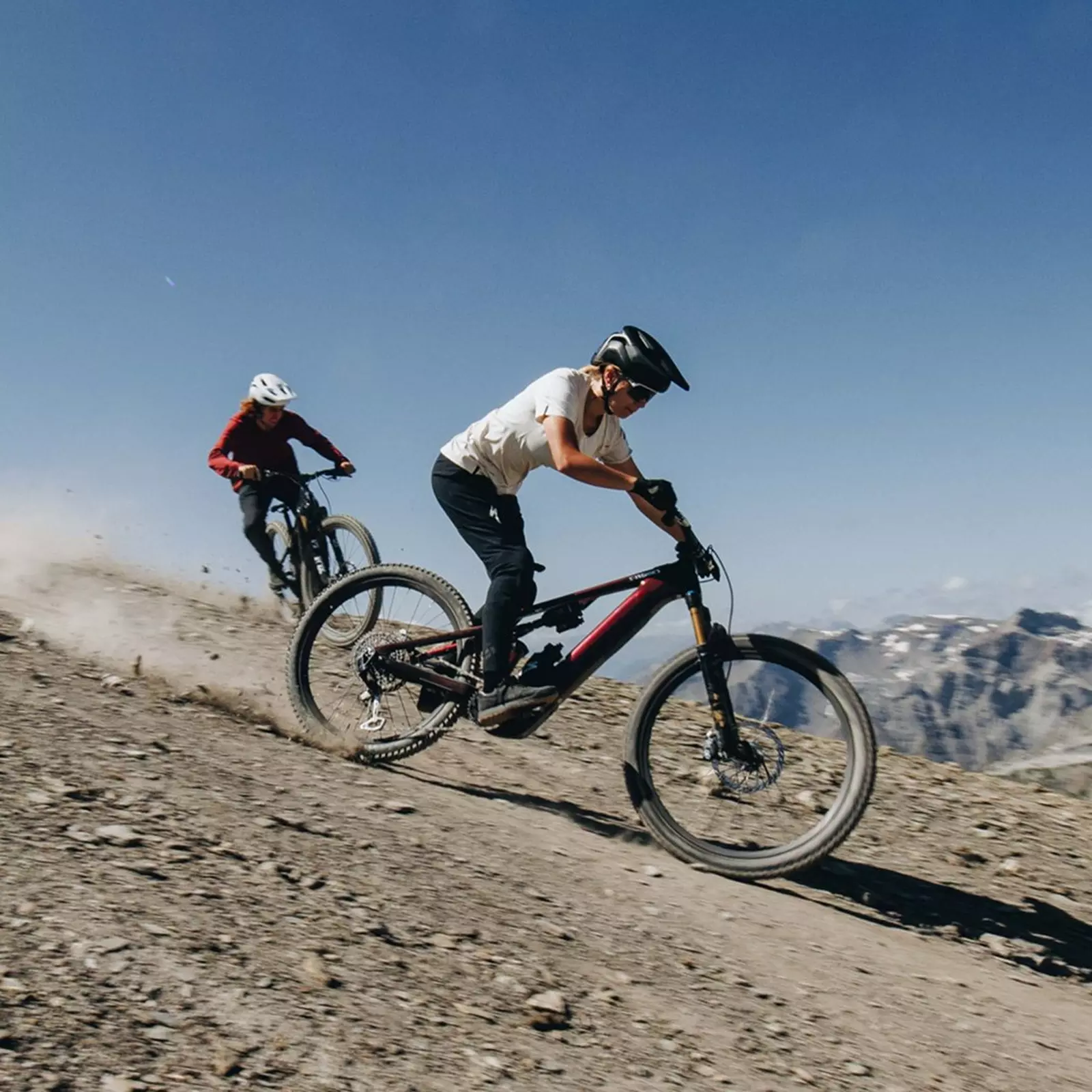 Dva jezdci na Specialized Turbo Levo sjíždějí horský trail pod modrou oblohou